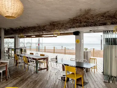 Vue intérieure d'un restaurant en bord de mer avec La Cloison Panoramique Glass Systems, le système de fermeture en verre de terrasse 