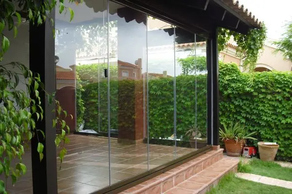 Aménagement de terrasse extérieur avec une fermeture en verre coulissante pivotante type Paroi en Verre Rétractable