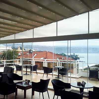 Aménagement d'une terrasse couverte d'un restaurant donnant sur la mer avec cloison vitrée coulissante pivotante