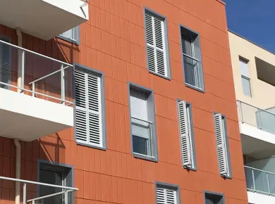 Installation de brise-soleil orientable en guise de volet pliant à lames orientables pour immeuble avec fenêtre et balustrade en verre.