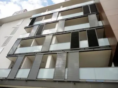 Cloison coulissante extérieure en aluminium gris anthracite à lames orientables installé en façade d'immeuble.