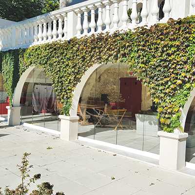 Fermeture d'une terrasse couverte comportant des arches avec un système type Rideau de Verre