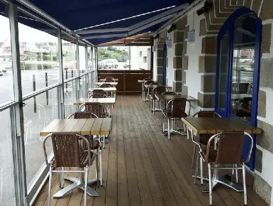 Terrasse couverte d'un restaurant avec paravents extérieurs télescopiques en guise de fermeture en verre panoramique